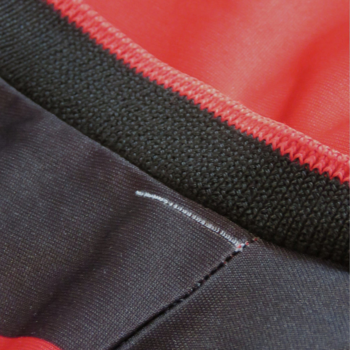 Detailopname van de zwarte geribbelde kraag en rode stof van het Nostalgic Football Shirts AC Milan 1990-91 thuisshirt